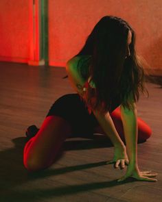 a woman is sitting on the floor with her hands behind her back and legs crossed