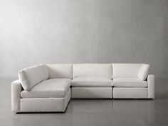 a white couch sitting on top of a gray floor next to a chair and ottoman