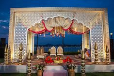 an outdoor wedding setup with white and red decor on the lawn at night time,