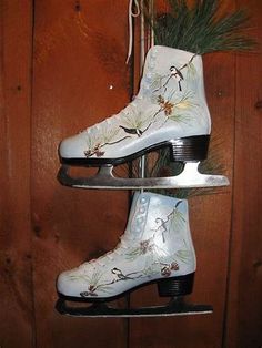 two white roller skates are hanging on a wooden wall with pine cones and needles