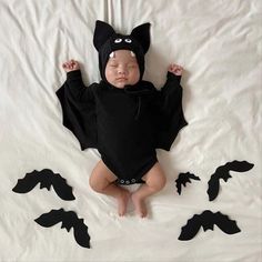 a baby wearing a bat costume laying on top of a bed