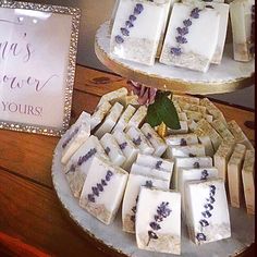 two trays filled with different types of soap on top of a wooden table next to a sign