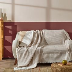 a living room with a couch covered in a blanket and an apple on the floor