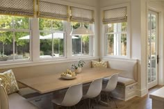 a dining room table with four chairs and a bench in front of the window that is open