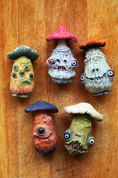 five different colored clay heads on a wooden surface