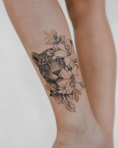 a woman's leg with a tattoo of a tiger and flowers on the side