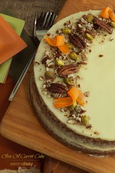 a cake with white frosting topped with nuts and carrots on a cutting board