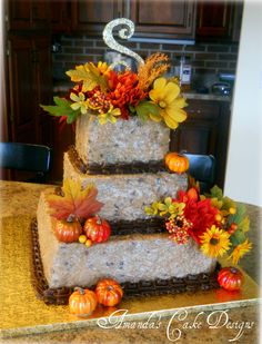 a three tiered cake decorated with fall leaves and pumpkins