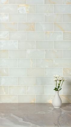 a vase filled with flowers sitting on top of a counter next to a tiled wall