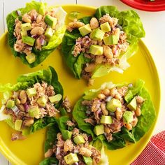 four lettuce cups filled with tuna and avocado salad on a yellow plate