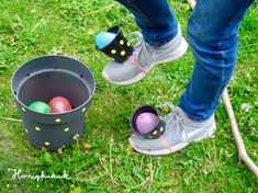 a person standing next to a bucket filled with easter eggs and an egg laying on the ground