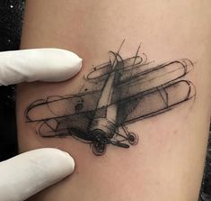 a woman's arm with a tattoo on it and an airplane in the background