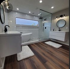 a bathroom with wood flooring and white tile on the walls, along with a walk in shower