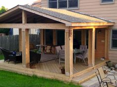 a wooden patio with chairs and table next to a house