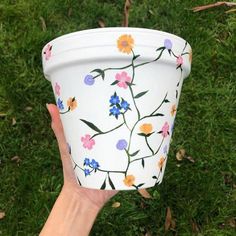 a hand holding up a paper cup with flowers painted on it