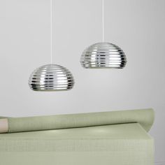 two circular lights hanging from the ceiling above a bed in a room with green sheets