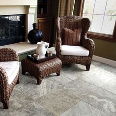 two wicker chairs sitting next to each other in front of a fire place with a vase on top of it