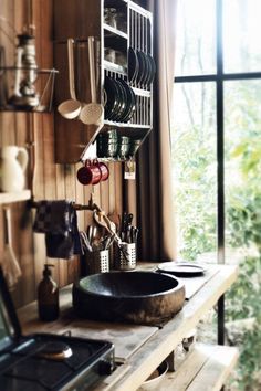 a stove top oven sitting next to a wooden shelf filled with utensils and pans