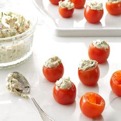 small tomatoes with cream cheese on them and a bowl of dip in the back ground