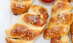 hotdogs wrapped in bread with sesame seeds and ketchup on the side