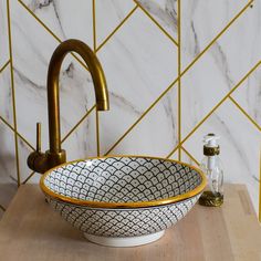 a white and gold bowl sink sitting on top of a wooden counter