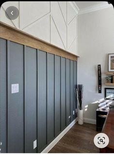 a room with a wooden table and gray paneling on the wall next to it