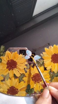 someone is painting sunflowers on a plate