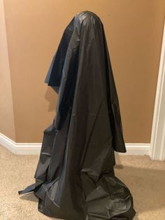 there is a black plastic bag on the floor next to a coat hanging from a wall