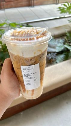 a person holding up a plastic cup with food in it and a label on the lid