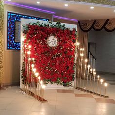 a red flower wall with candles in front of it