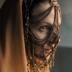 a close up of a person with jewelry on their face and in a veil over her head