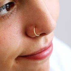 a close up of a person with a nose ring on their nose, wearing a white shirt