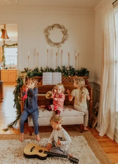 three children sitting on a couch playing with musical instruments in front of a christmas tree