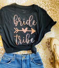 a t - shirt that says bride tribe on it next to some jeans and shoes