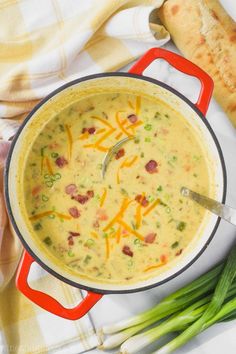 a pot filled with soup next to green onions and bread