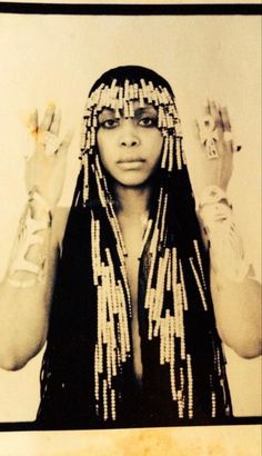 an old photo of a woman with beads on her head and hands in front of her face