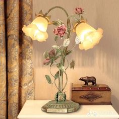 a vase with flowers on top of a table next to a box and lamp shade