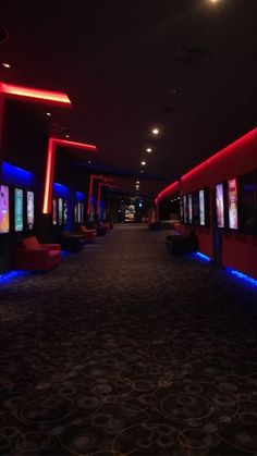 an empty room with red and blue lights on the walls, chairs and televisions