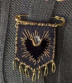 a close up of a person wearing a sweater with a heart shaped pin on it