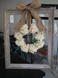 a wooden frame with a wreath hanging on the front of it and a ribbon tied around the top