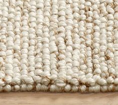 a close up of a rug on a wooden floor with white and tan colors,