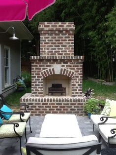 an outdoor fireplace with chairs around it