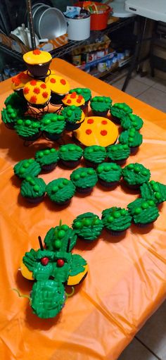 the table is covered with cupcakes decorated like animals and plants on orange paper