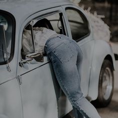 a woman leaning on the side of a car with her hand in the door window