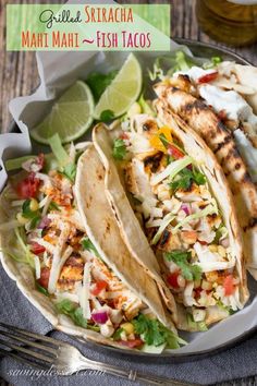 grilled fish tacos on a plate with limes and cilantro in the background