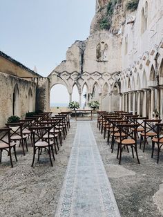 rows of wooden tables and chairs in an old building with stone arches on the side