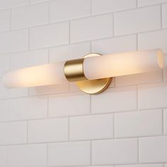 a bathroom light that is on the wall next to a white brick wall and floor