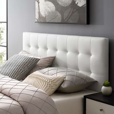 a white bed sitting next to a window in a room with gray walls and furniture