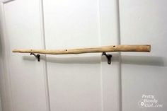 a piece of wood is hanging on the wall next to a pair of hooks and a door handle