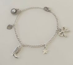 This Coastal Cowgirl Silver Charm Bracelet is the perfect accessory for every outfit. This dainty bracelet boasts an eclectic mix of charms, including a cowgirl boot charm for the coastal cowgirl, a delicate heart charm, a chic bow charm, a radiant star charm, and a seashell charm that ties all the pieces together. Get this charm bracelet for everyday wear or for the perfect gift! Charm Jewelry Silver, Silver Charm Bracelet Aesthetic, Silver Charm Bracelets, Charm Bracelet Ideas, Bracelets Hippie, Charm Bracelet Silver, Bracelet With Charms, Cowgirl Boot, Hippie Bracelets